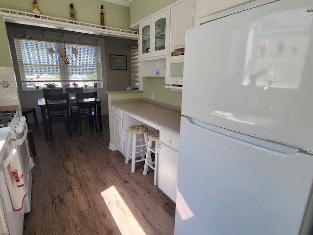 kitchen featuring white appliances, white cabinets, dark wood-style floors, light countertops, and built in desk