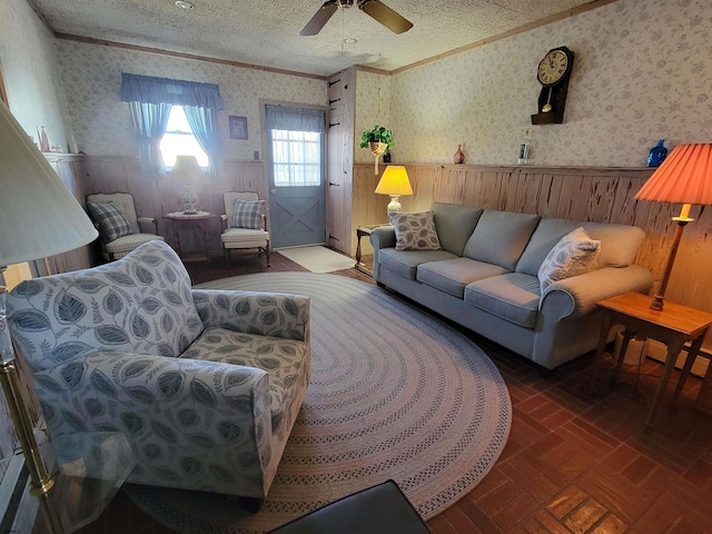 living room with a wainscoted wall, brick patterned floor, crown molding, and wallpapered walls