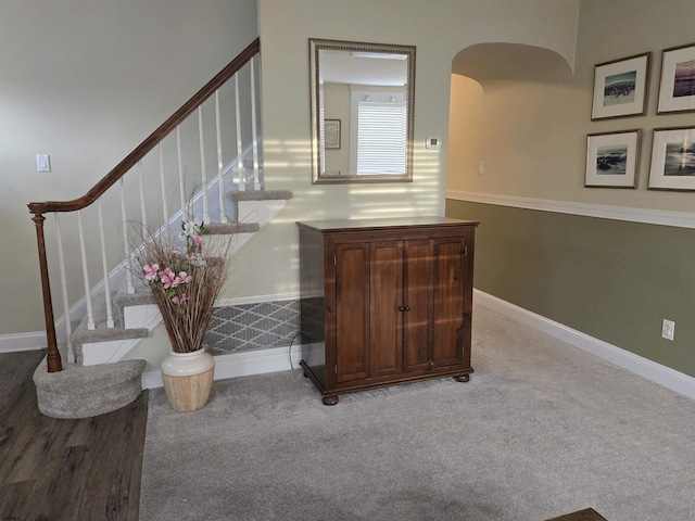 staircase with carpet, arched walkways, and baseboards