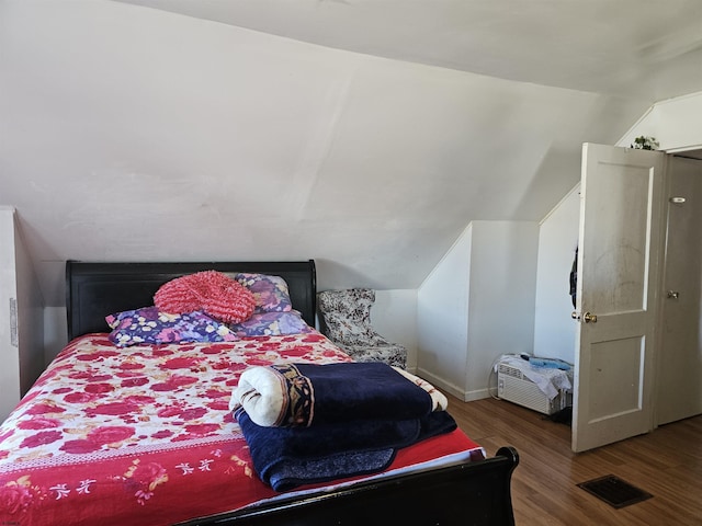 bedroom with visible vents, vaulted ceiling, and wood finished floors