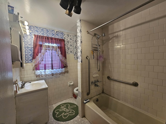 bathroom featuring tile walls, toilet, washtub / shower combination, vanity, and tile patterned floors