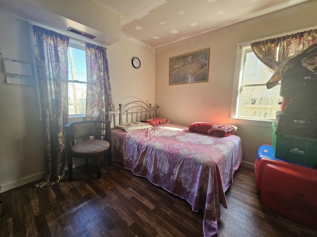 bedroom with multiple windows, wood finished floors, visible vents, and baseboards