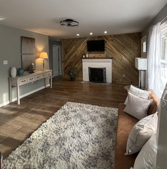 living area with recessed lighting, a brick fireplace, wooden walls, and wood finished floors