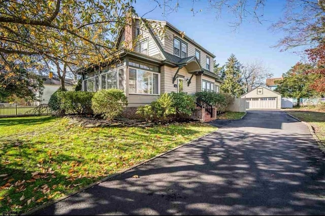 view of front of house featuring a gambrel roof, fence, a garage, an outdoor structure, and a front lawn