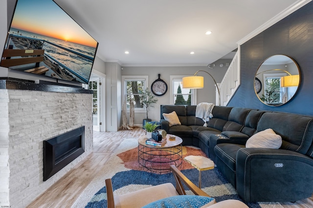 living area with stairs, a stone fireplace, ornamental molding, and wood finished floors