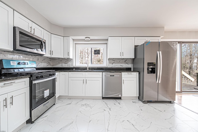 kitchen featuring a healthy amount of sunlight, marble finish floor, appliances with stainless steel finishes, and a sink