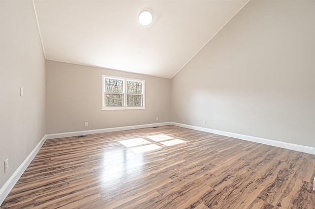 unfurnished room with lofted ceiling, wood finished floors, and baseboards