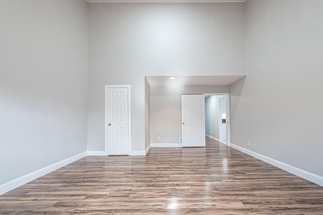 empty room with a high ceiling, wood finished floors, and baseboards