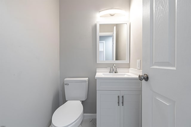 half bathroom with toilet, marble finish floor, baseboards, and vanity