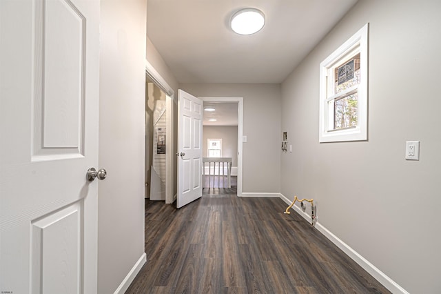 corridor with dark wood-style floors and baseboards