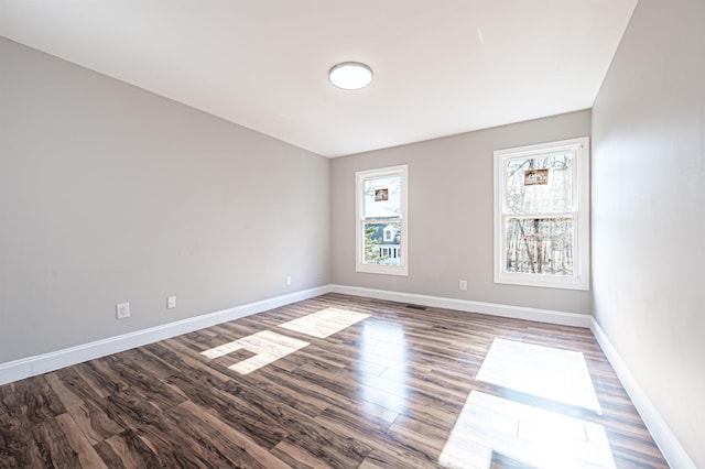 spare room featuring visible vents, baseboards, and wood finished floors