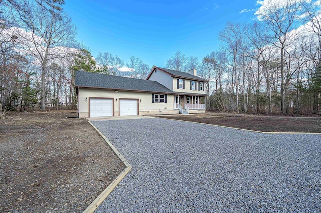 view of front of property with covered porch, a chimney, gravel driveway, and a garage