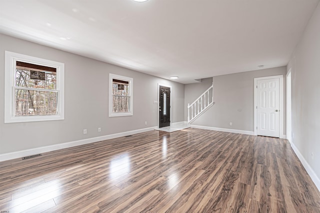 spare room featuring baseboards, visible vents, stairway, and wood finished floors