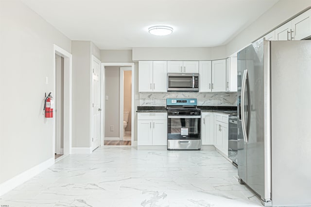 kitchen featuring white cabinetry, marble finish floor, appliances with stainless steel finishes, backsplash, and dark countertops