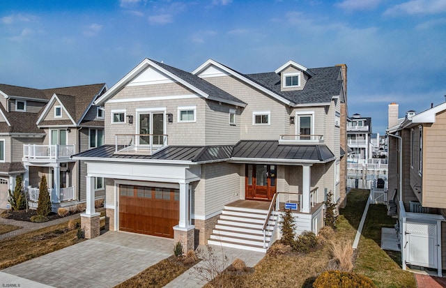 view of front of home with a garage, a balcony, a standing seam roof, decorative driveway, and french doors