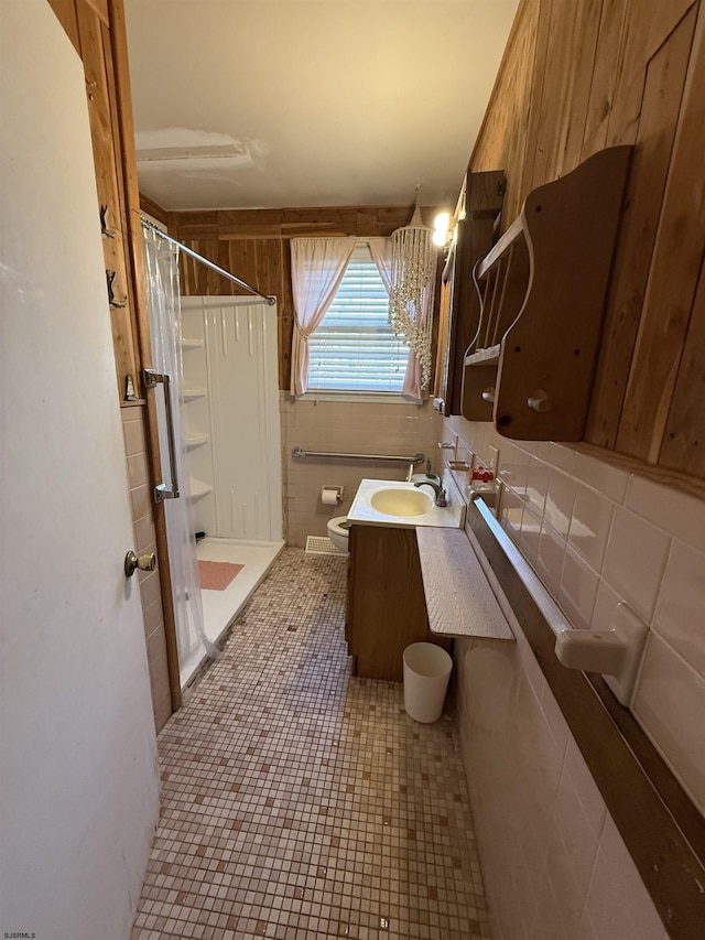 bathroom featuring decorative backsplash, toilet, vanity, wood walls, and a shower stall