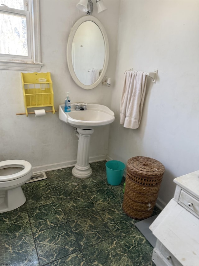 half bath featuring baseboards, visible vents, and toilet