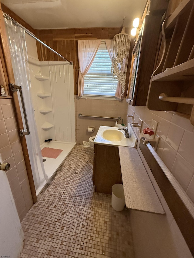 full bath with tile patterned flooring, a shower stall, tile walls, and vanity