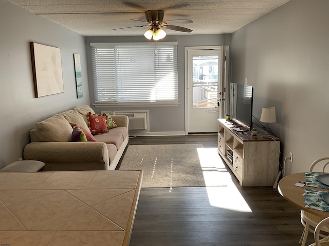 living room featuring ceiling fan, a textured ceiling, wood finished floors, a wall mounted air conditioner, and baseboards