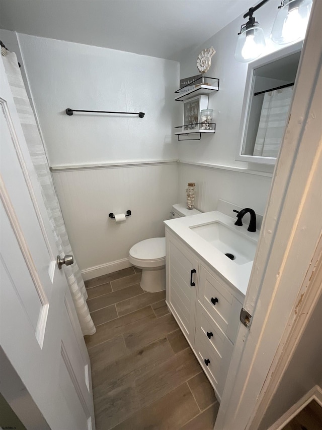 full bath with wood tiled floor, a wainscoted wall, vanity, and toilet