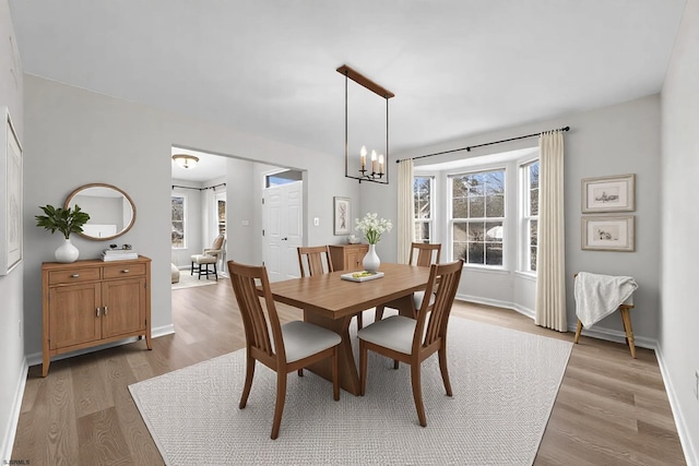 dining area featuring light wood-style floors, a chandelier, and baseboards