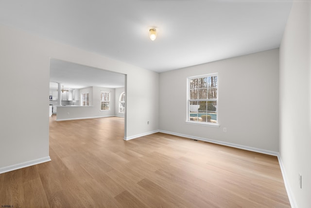 spare room with light wood-type flooring, a wealth of natural light, and baseboards