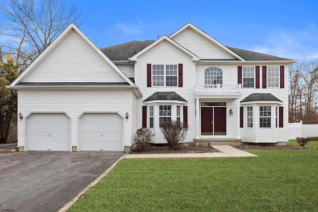 view of front of house with aphalt driveway, a balcony, a garage, a shingled roof, and a front yard