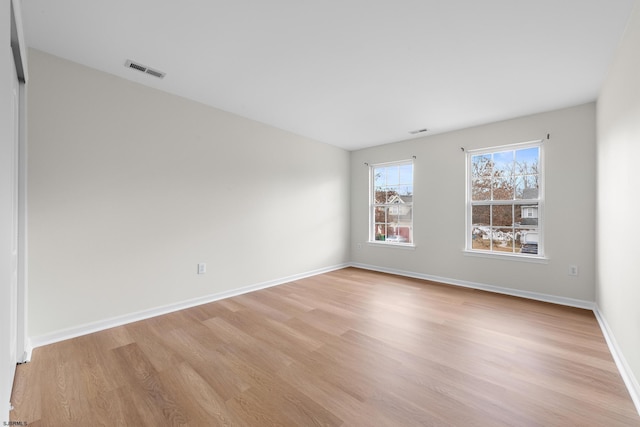 empty room featuring light wood-style floors, visible vents, and baseboards