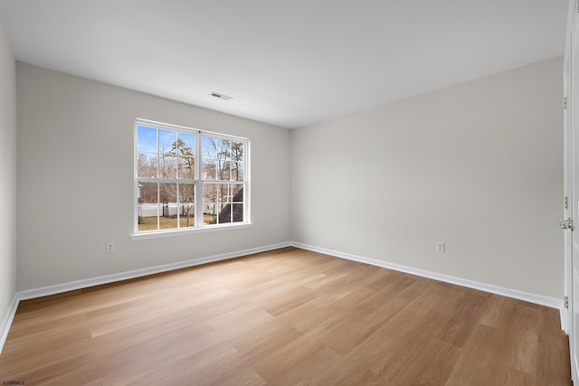 unfurnished room featuring visible vents, light wood-style flooring, and baseboards