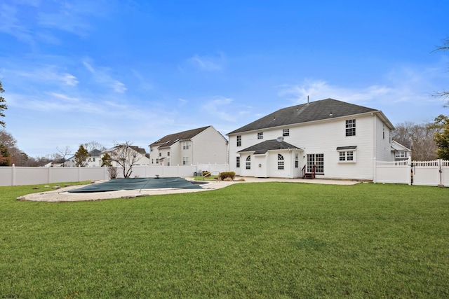 back of house featuring a fenced in pool, a fenced backyard, a patio, and a lawn