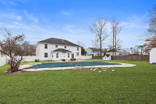 back of property featuring a fenced in pool, a fenced backyard, an outdoor structure, and a shed