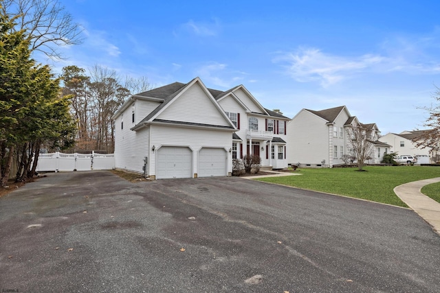 view of front of house featuring aphalt driveway, an attached garage, a gate, fence, and a front yard
