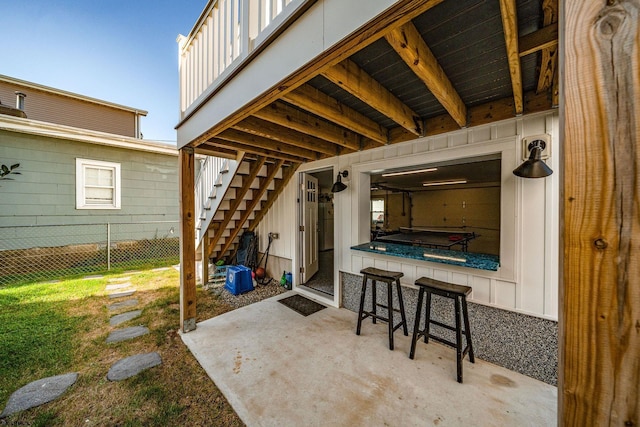 view of patio featuring fence and stairway