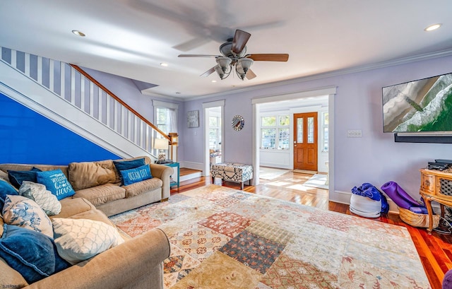 living area with recessed lighting, wood finished floors, baseboards, ornamental molding, and stairway