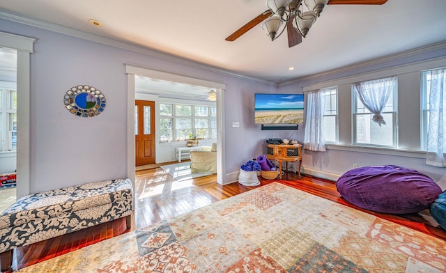 bedroom with baseboards, wood finished floors, a ceiling fan, and crown molding