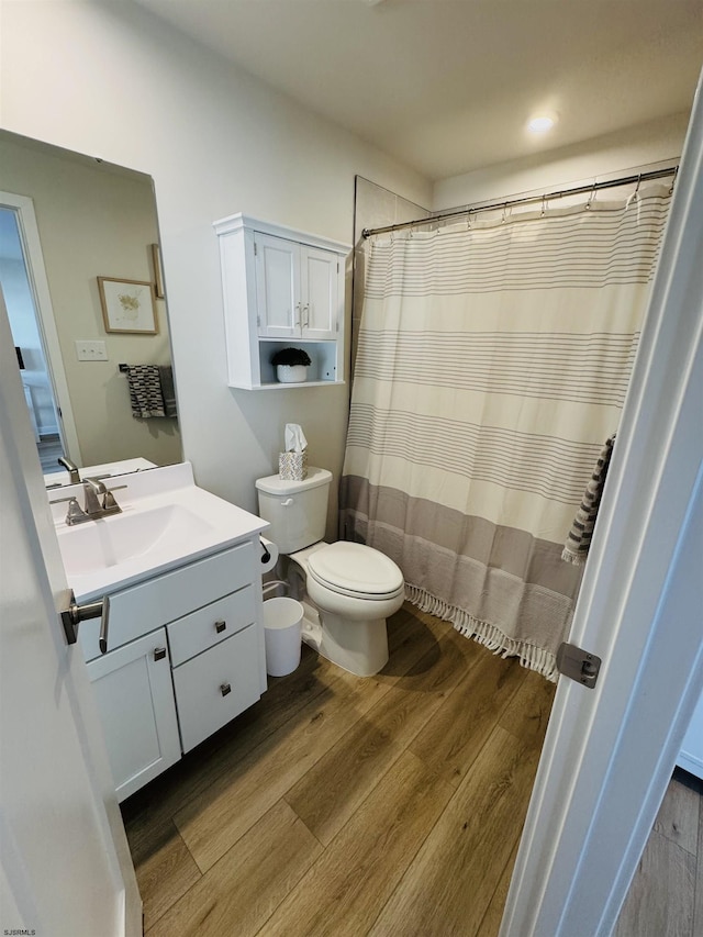 bathroom with vanity, curtained shower, wood finished floors, and toilet