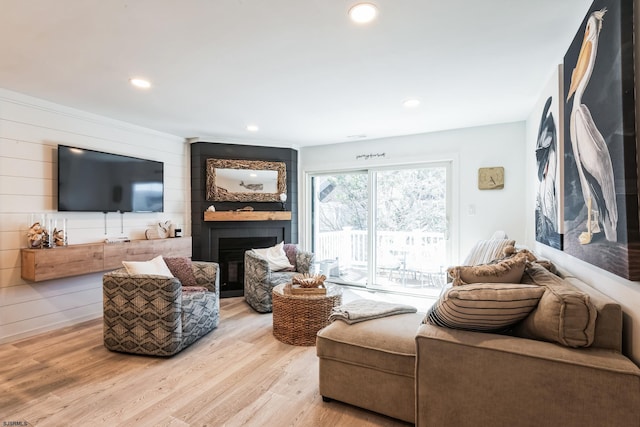 living area with recessed lighting, a fireplace, wood walls, and wood finished floors