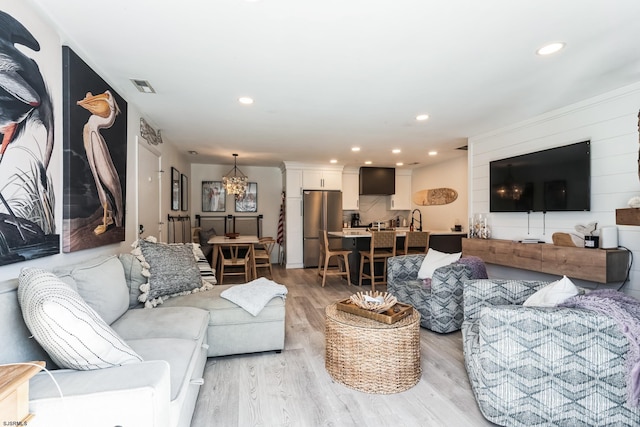 living area with light wood finished floors, visible vents, and recessed lighting