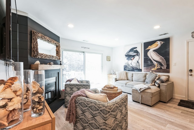 living room featuring recessed lighting, a fireplace, and light wood-style floors