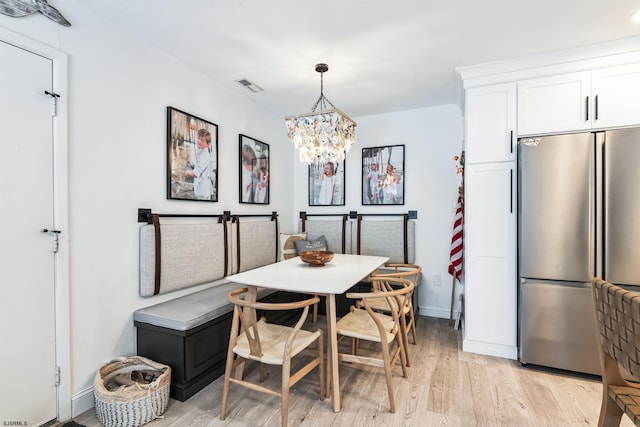 dining space with a chandelier, visible vents, light wood-style flooring, and baseboards