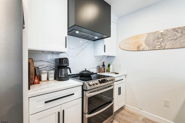 kitchen featuring tasteful backsplash, double oven range, premium range hood, and white cabinetry