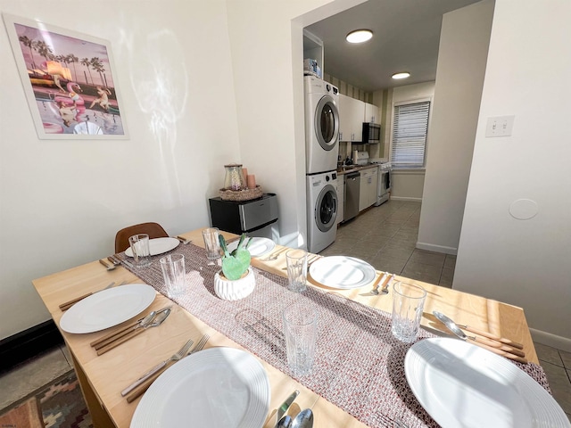 bathroom featuring stacked washer / drying machine, tile patterned floors, baseboards, and double vanity