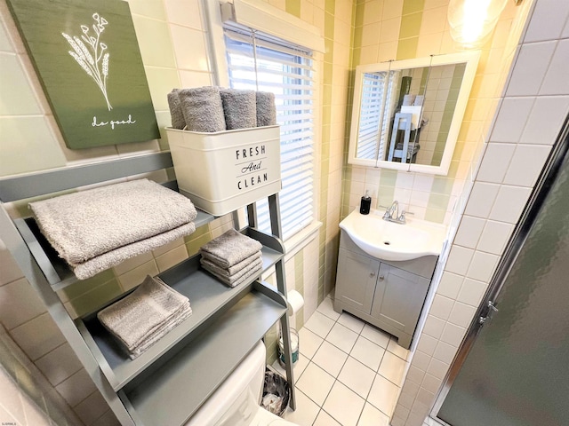 bathroom with a stall shower, tile patterned flooring, tile walls, and vanity