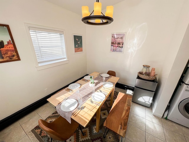 tiled dining space with stacked washer and dryer and baseboards