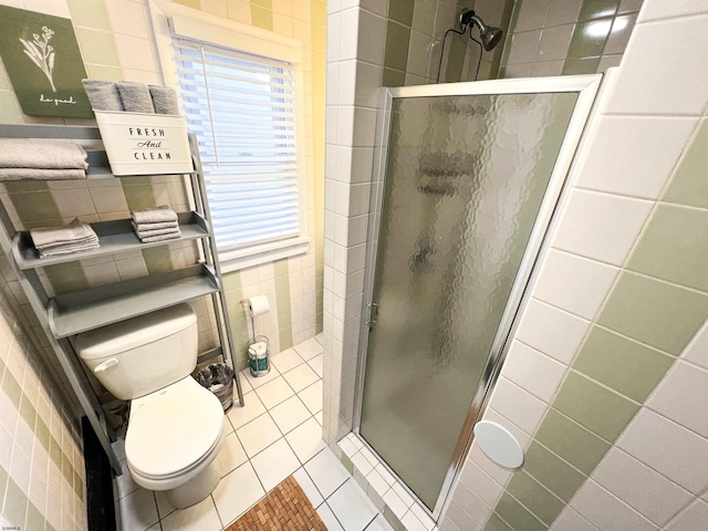 bathroom featuring tile walls, a wealth of natural light, toilet, a shower stall, and tile patterned floors