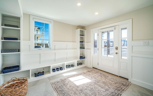 mudroom with built in shelves, wainscoting, recessed lighting, and a decorative wall