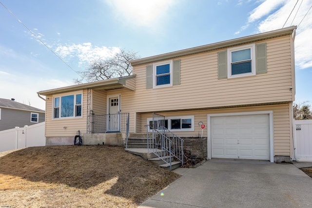 tri-level home with a garage, driveway, and fence