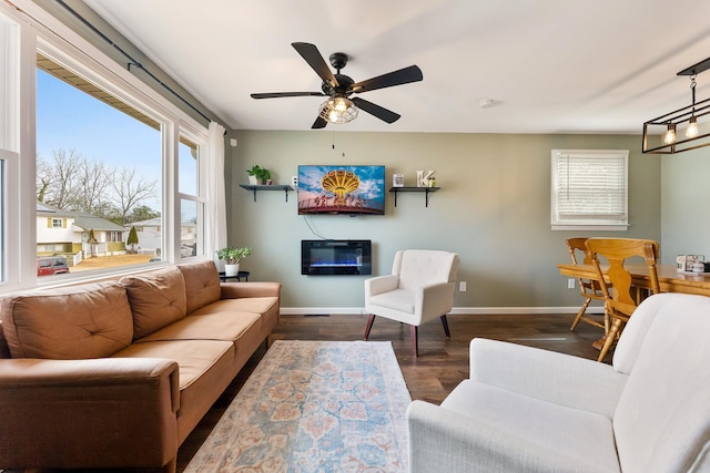 living area featuring ceiling fan, baseboards, and wood finished floors