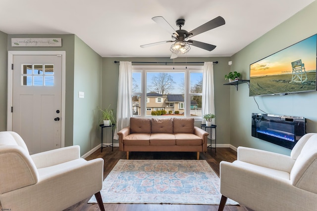 interior space with a ceiling fan, baseboards, and wood finished floors