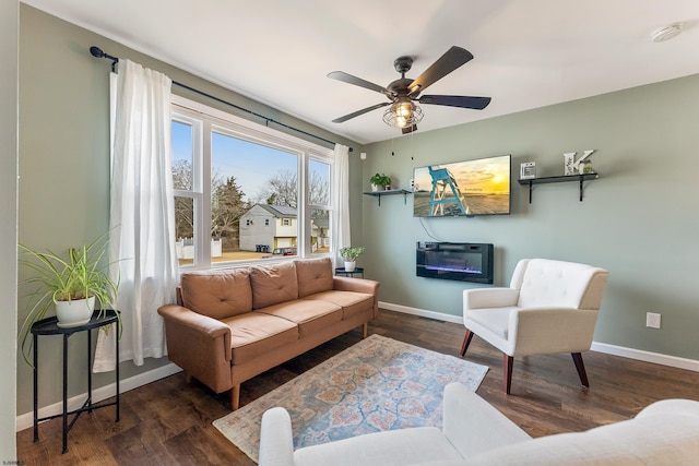 sitting room with baseboards, wood finished floors, and a glass covered fireplace